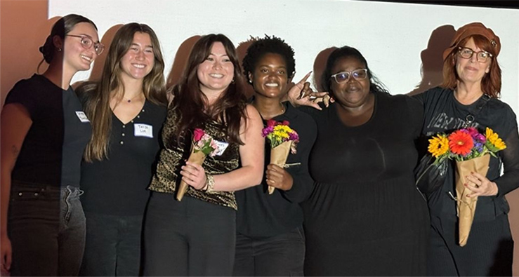 group of people dressed in black smile with arms linked