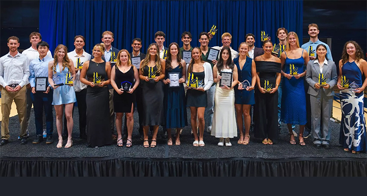 A large group of student athletes pose on stage wearing smiles and formal attire at the UC San Diego Triton Athletics Awards June 2026