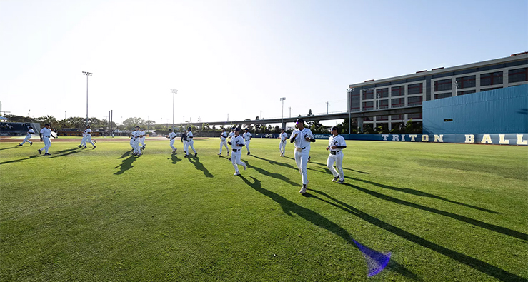 Triton baseball team practices on the outfield -- a bright sunbeam cuts through the sky