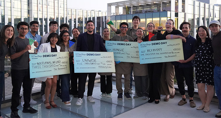 Large group of UCSD students hold giant checks in the Basement's Demo Day event 2025