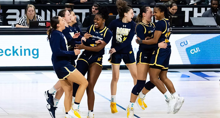 UC San Diego Triton women's basketball team members jump and celebrate at center court