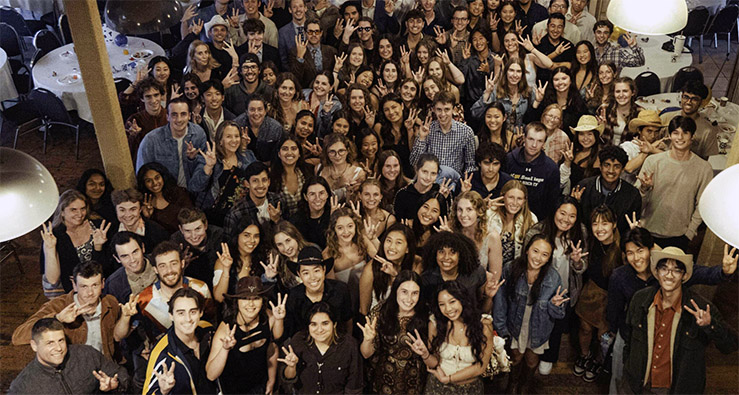 Overhead group photo of a very large group of UCSD students smiling and waving to camera