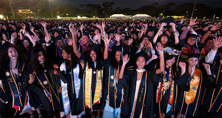 Large group of cheering UCSD grads in their black caps and gowns