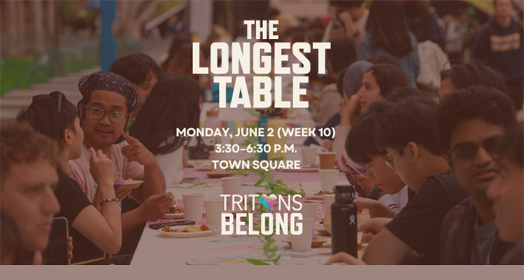 A large group of UCSD students surround a dining table, talking and smiling