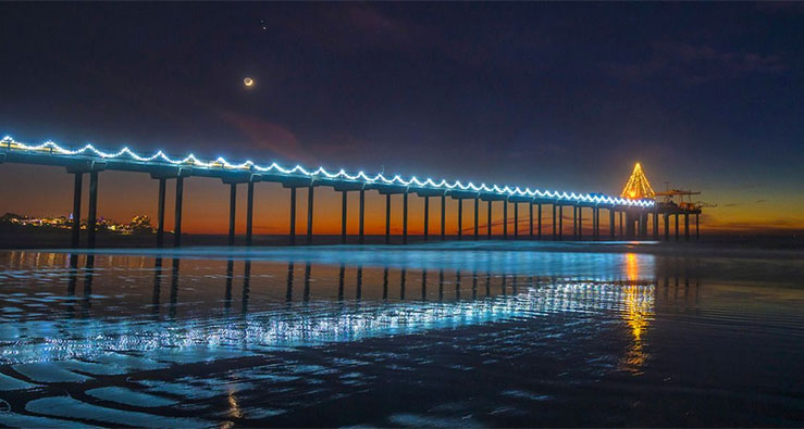 Scripps Pier at night, with holiday lights reflected in the sea below