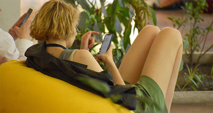 A young female with a mobile phone sitting on the bag chair in the conference lounge room.