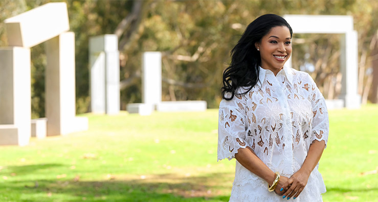 Mashonda Tifrere stands in a white dress before the very large Stuart Collection sculpture on Revelle lawn - photo by Erik Jepsen