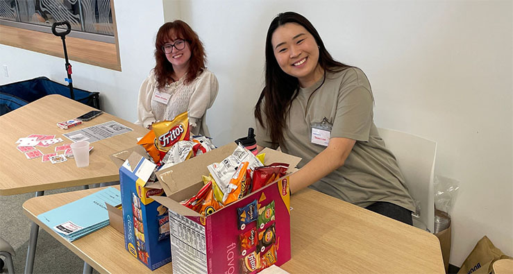 Two smiling UCSD students sit at a table with snacks