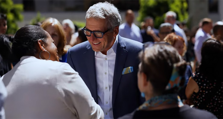 University of California President smiles and shakes hands with a small group of people