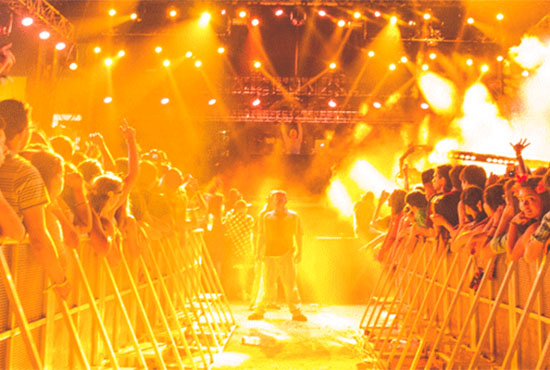 With golden light surrounding all, a musical performer takes the mic before a cheering crowd at Sun God Festival, UC San Diego